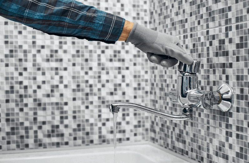 Plumber holding faucet in bathroom for sustainable plumbing business